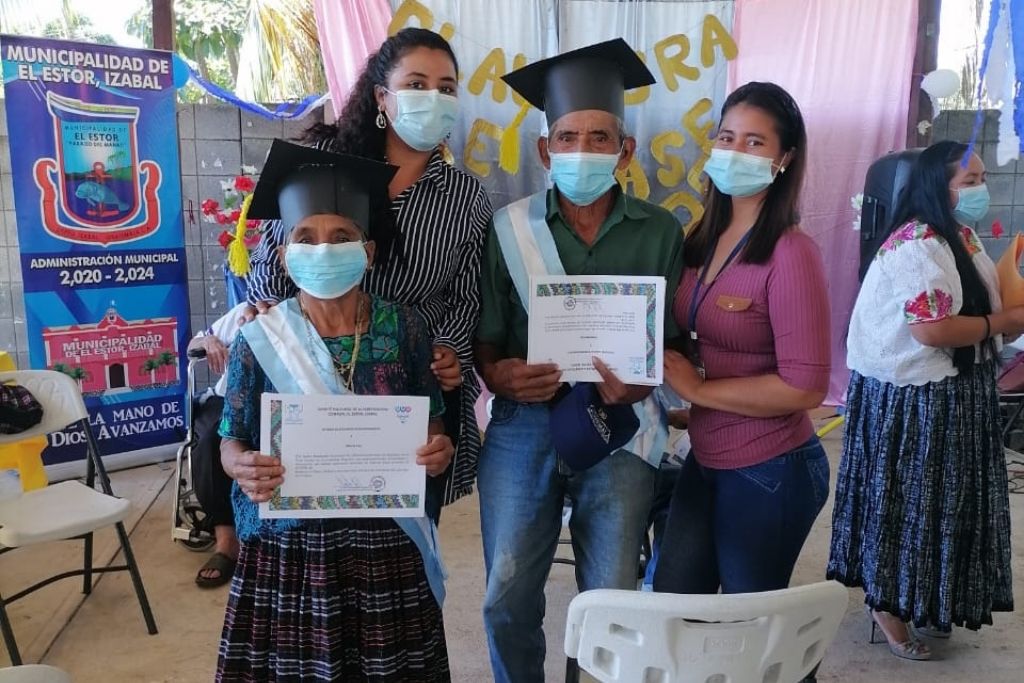 Adultos mayores mostrando su diploma de primaria en el Estor, Izabal